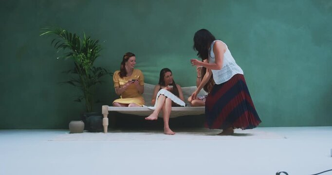 Woman serving tea cup to friend and joining group conversation