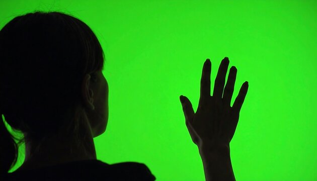 Womans Silhouette Touching a Futuristic Green Screen Interface. - Powered by Adobe