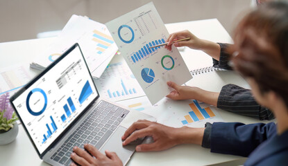 Collaborative Analysis. Professionals discussing financial data with reports and laptop.