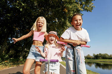 Three joyful children enjoying a sunny day outdoors with smiles and laughter