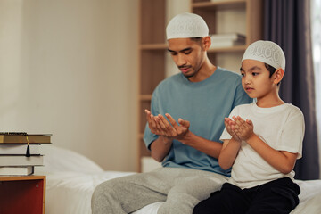 A young Muslim boy learning to pray beside his father, illustrating Islamic teaching, family bond,...
