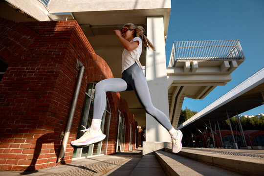 Woman jumping outdoors during a fitness workout near a modern urban structure