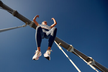 Woman exercising outdoors wearing leggings and sneakers with a blue sky background