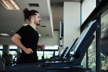 Young man running on treadmill in the gym