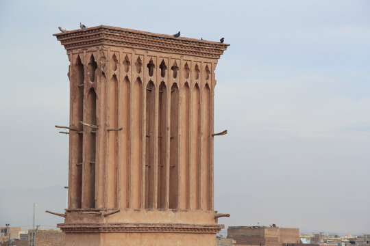 Historic windcatcher tower in Yazd, Iran, featuring traditional Persian mudbrick architecture and desert heritage against a cloudy sky.