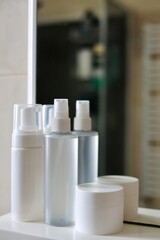 Care products, cosmetics and comb on the shelf in white bathroom. Cleanser, lotion, cream and comb near mirror. White bathroom. Women care products. Yellow comb. 