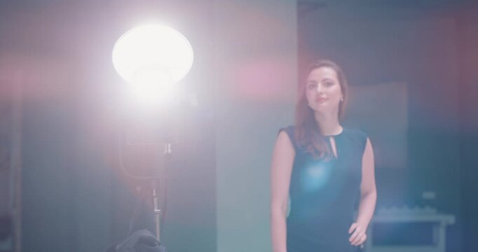 Camera pans across photo shoot crew with lighting setup and model in studio