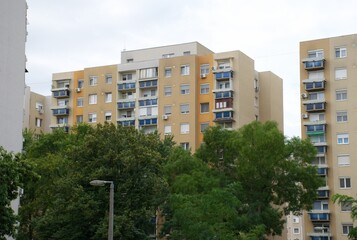 Green urban park , trees, benches, and lamppost, panel apartment blocks. Typical Eastern European housing estate architecture, community space and urban greenery. Block of flats, Balkan Eastern-Europe