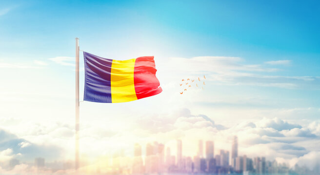 Chad flag wavering in beautiful clouds with building skyline. The flag with drone shot in beautiful sky. Chad national flag for independence day. - Powered by Adobe