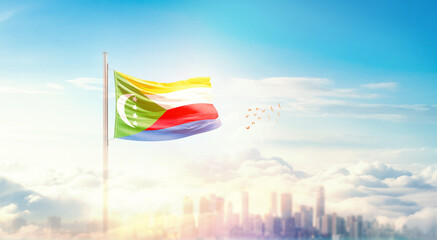 Comoros flag wavering in beautiful clouds with building skyline. The flag with drone shot in...