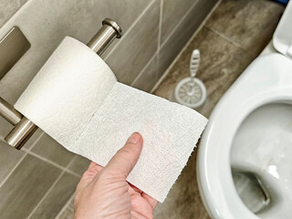 Hand reaches for toilet paper in a contemporary bathroom setting during the day