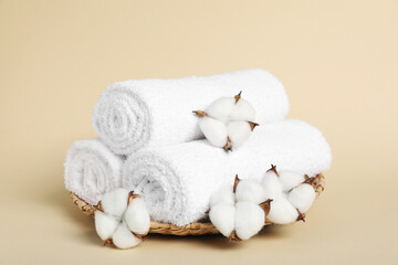 Rolled towels and cotton flowers on beige background, closeup
