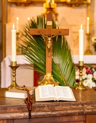 Wooden cross, open bible, candles, and palm branch on altar