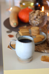 Lit candles, cookies, chocolate, nuts, tea, wine, pumpkins, books, reading glasses and autumn leaves on the table. Autumnal hygge at home. Selective focus.