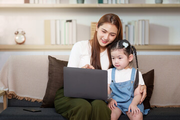 Mother and daughter bonding over laptop in cozy living room