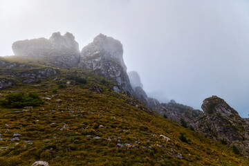 landscape with a rocky mountain ridge in fog during rain