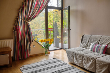 Cozy living room with a view of nature through open doors and a balcony.