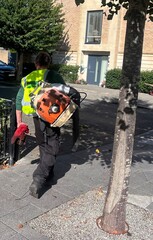 A petrol powered professional leaf blower on the back of a council worker or gardener.