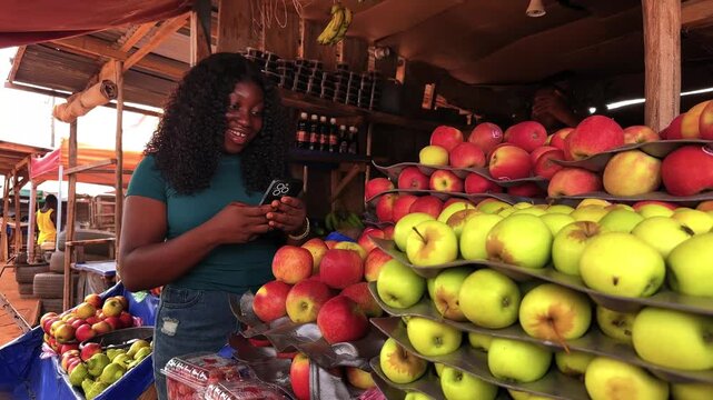 side view video of young black african woman using mobile phone inside stall market