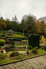 Fototapeta premium Scenic view of a beautifully landscaped garden with lush greenery and a gazebo.