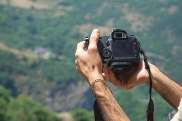 Photographer holding a digital camera taking pictures in nature.