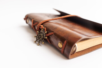 Vintage leather travel journal treatise with embossed compass motif ideal for travel writing, sketching or diary reflections, shown against neutral backdrop emphasizing texture, closure strap