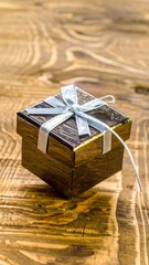 Small, square, brown gift box with light gray ribbon