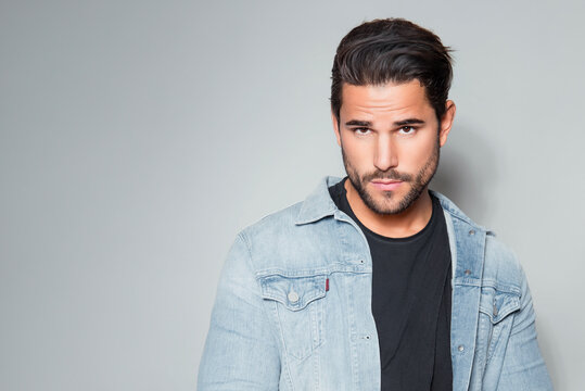 Handsome young man with dark hair and beard posing in casual clothes