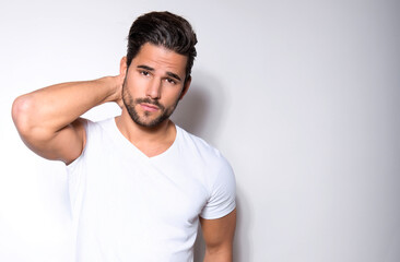 Handsome young man with dark hair and beard posing in casual clothes