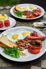 Delicious breakfast with fried eggs, beans, and grilled tomatoes on a white plate.