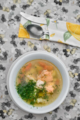 Delicious salmon soup served in a white bowl with fresh herbs and vegetables.