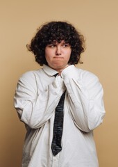 Young person with curly hair stands nervously against a neutral background during a formal event © bodnarphoto