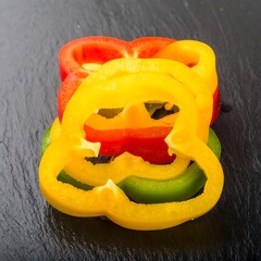 Colorful bell pepper slices on dark slate