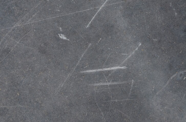 This detailed photograph captures the imperfection of a dark gray texture, marked by numerous...