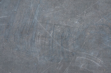 Fototapeta premium A close-up of a heavily scratched and scuffed dark gray surface, featuring light-colored abrasions and arcing scrapes, perfect for a rugged, worn background.