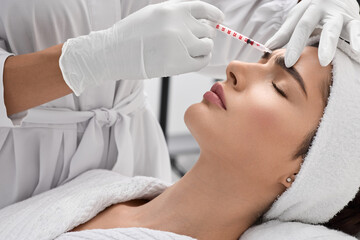 Naklejka premium Pretty female while facial mesotherapy for wrinkles removal, side view. Beauty injections in woman's forehead for blocking mimic wrinkles