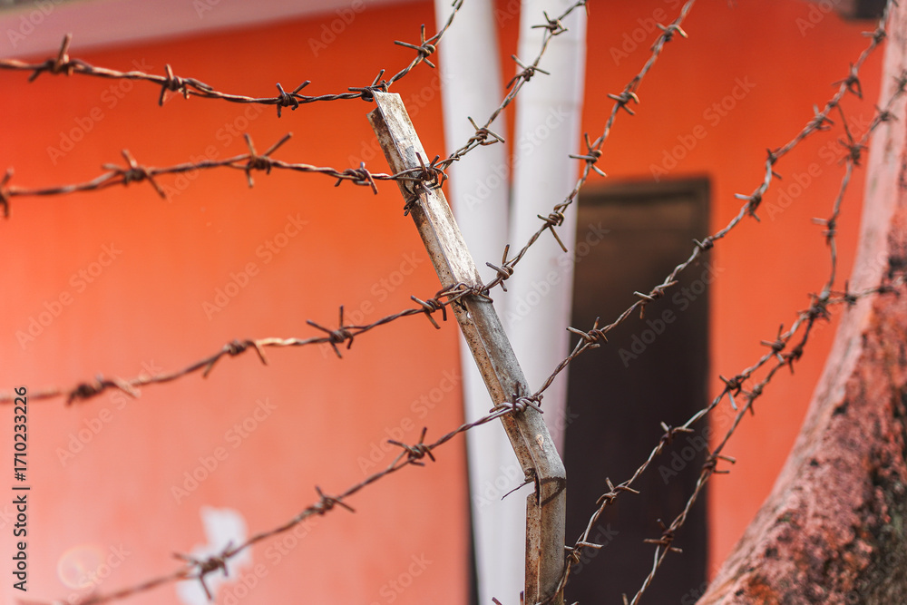 Poster detailed close-up of rusty barbed wire secured with weathered metal post, showcasing texture and pat