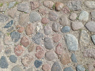 Old cobblestone pavement with natural stones and grass