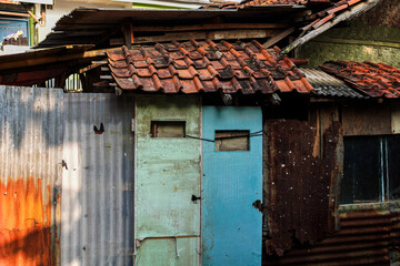 Weathered facade featuring aged materials, showcasing a textured wall with corrugated iron, worn doors, and rusted metal, isolated in white background for versatile creative use.