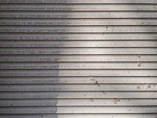 Obraz premium Metal roller shutter door with sunlight and shadows