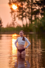 Fototapeta premium Young woman enjoys water at sunset