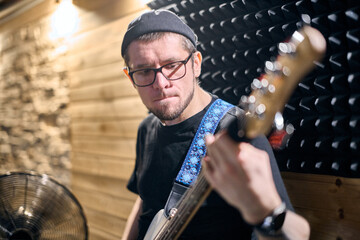 Young male guitarist in focused music rehearsal