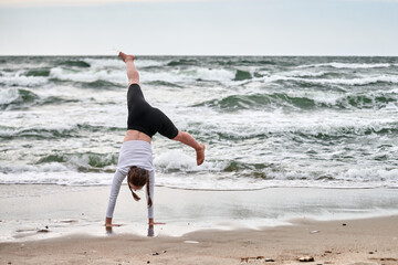 Young girl performs cartwheel on baltic sea beach