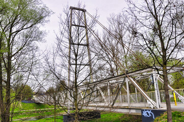Ostrawa - most nad rzeką Ostravice. Malownicza kładka dla pieszych otoczona bezlistnymi drzewami i trawiastymi terenami, idealna do zdjęć podróżniczych i eksploracyjnych. © Pol Badger