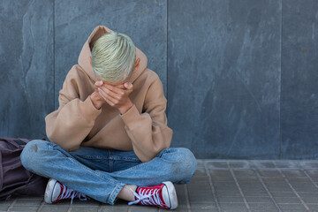 Lonely teenager sitting on the floor outdoors