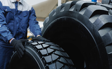 Mechanic handling heavy duty tire in mining industry, concept Maintenance service replacing on...