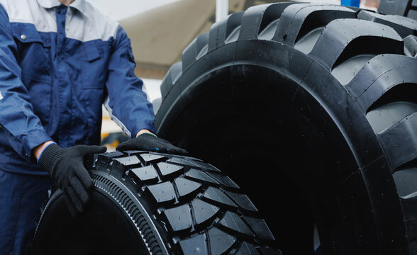 Mechanic handling heavy duty tire in mining industry, concept Maintenance service replacing on wheels