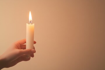 Hand Holding Lit Candle: A single lit candle held delicately in hand casts a warm, inviting glow, symbolizing hope and remembrance in a serene, contemplative scene. 