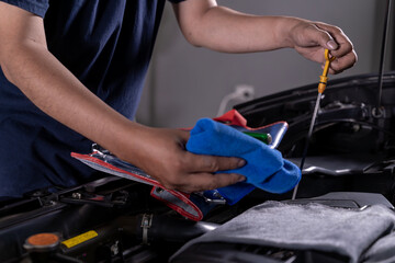 Young man inspecting the engine oil level of his car for regular maintenance and vehicle safety