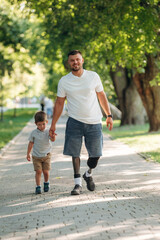 Fototapeta premium Father that is amputee with prosthesis is with his little son in the park